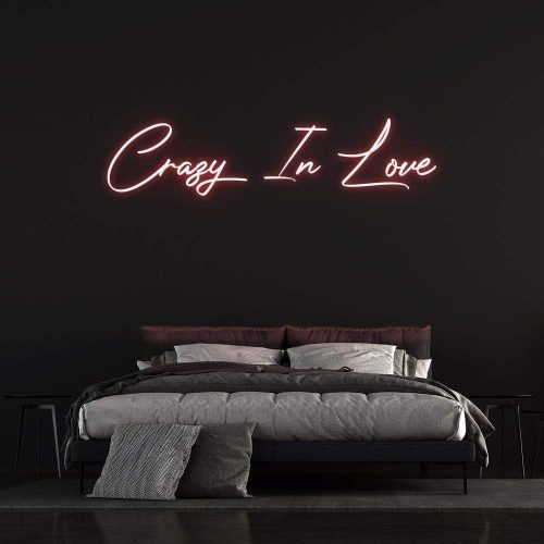 "Crazy In Love" LED Neon Sign glowing in pink, creating a romantic ambiance as modern wall decor above a bed.