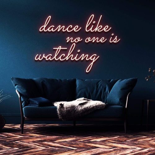 Warm white neon sign reading 'Dance like no one is watching' above a contemporary blue sofa in an elegant interior setting.